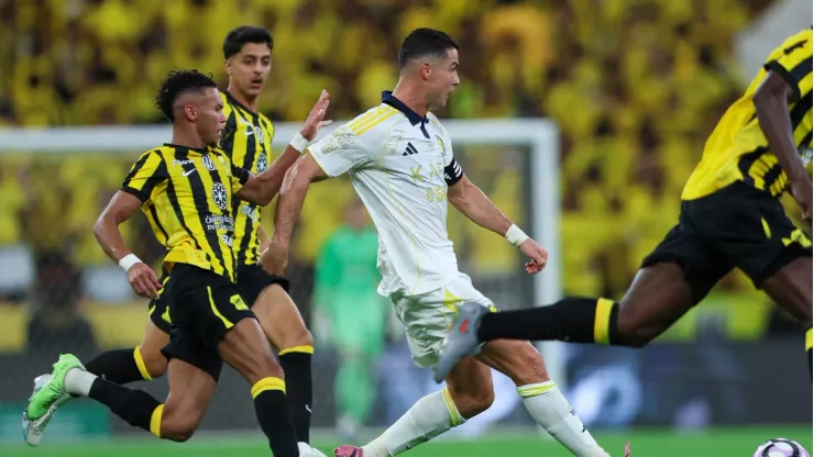 Cristiano Ronaldo y Karim Benzema disputando el balón en un partido de futbol; hoy se enfrentan Al-Nassr y Al-Ittihad en Arabia Saudita.