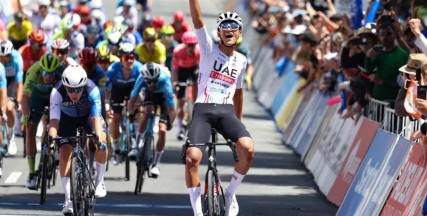 Isaac del Toro levanta los brazos en señal de victoria durante una competencia europea de ciclismo.
